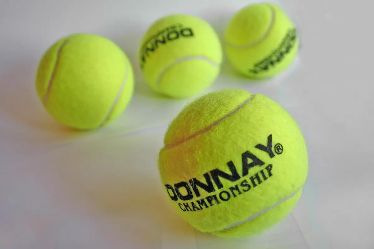 Pelota de tenis amarilla sobre fondo neutro.